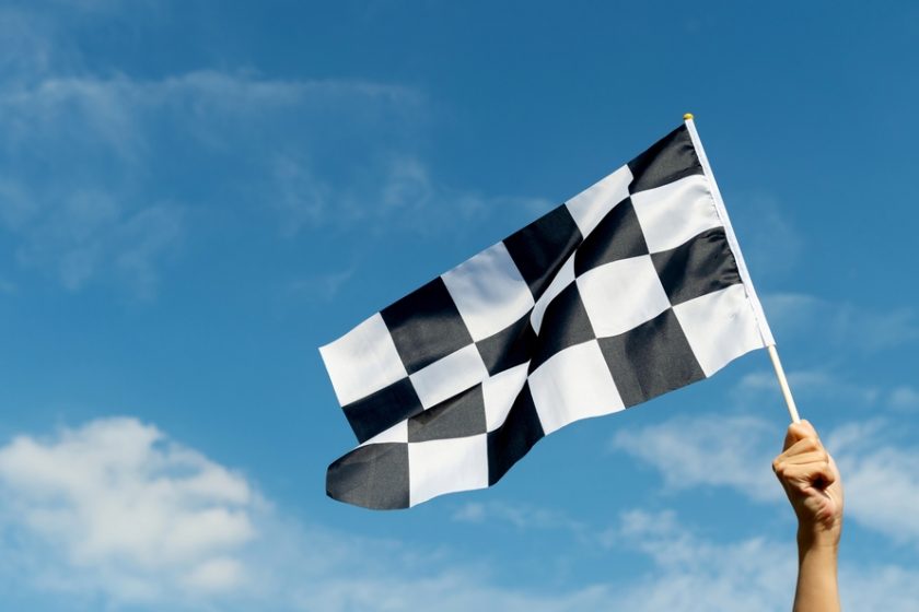 Raceflagga i hand som viftar vid himmelen